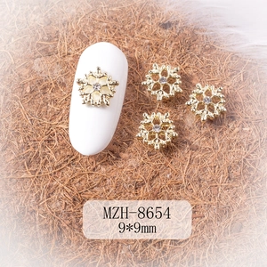 Macro view of 9mm gold snowflake nail charms with crystal center for winter DIY manicure