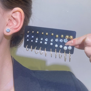 Detailed set of gold earrings with pearls and crystals shown on display card and model
