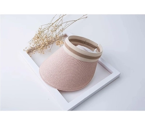 Dettaglio del cappello da sole intrecciato rosa con trama fine in paglia e nastro a righe