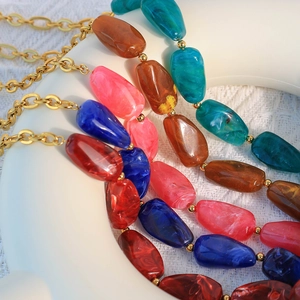Multicolor marble resin bead necklace with gold stainless steel chain in flat lay view