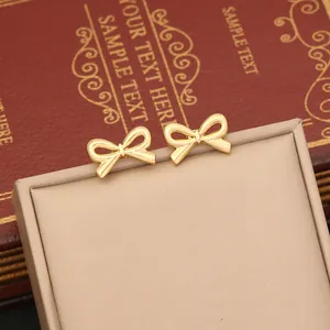 Detailed macro shot of elegant golden bow stud earrings on a luxury gift box