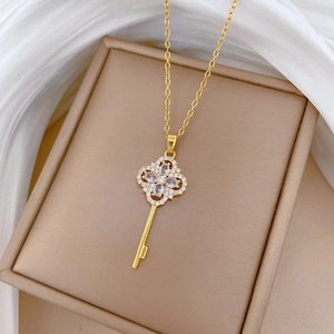 Elegant gold clover key necklace with sparkling crystals on a premium silk display