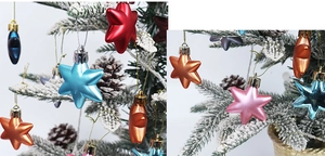 Close-up of shiny electroplated star ornaments in multiple colors on a snowy Christmas tree