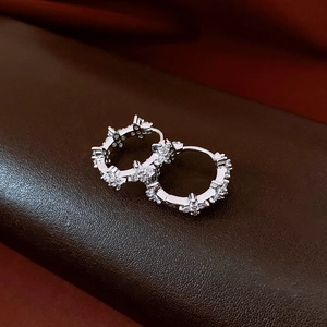 Gros plan de boucles d'oreilles fleurs en argent avec pavé de zircons sur fond cuir