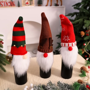 Close-up of three knitted Christmas gnome wine bottle covers with stripe and reindeer patterns