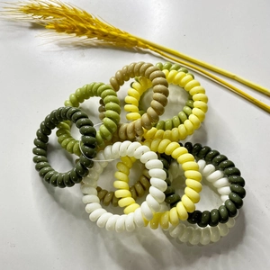Macro detail of elastic spiral hair ties in assorted green and white natural colors