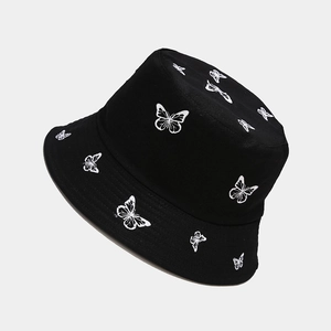 Close-up of white butterfly embroidery detail on black cotton reversible bucket hat
