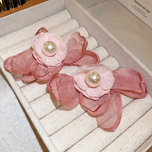 Detail view of pink chiffon flower earrings with pearls on a jewelry display stand