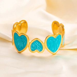 Macro detail of 18K gold-plated bangle featuring teal enamel heart-shaped charms