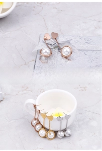 Detailed view of heart-shaped pearl drop earrings in rose gold, gold and silver finishes