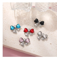 Detail of colorful bow heart pendants with rhinestones on a textured stone surface