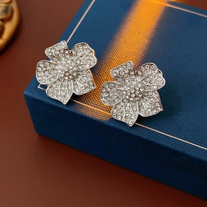 Macro shot of silver flower earrings with crystals on a navy blue jewelry box