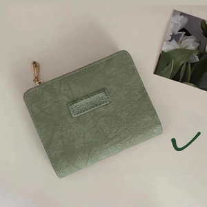 Detail of sage green vintage wallet featuring grainy texture and a small zip closure