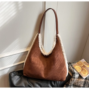 Detail of brown suede tote bag with white faux shearling trim and leather handles