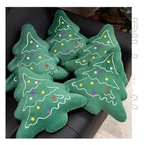 Set of six soft green plush Christmas tree pillows with colorful embroidery on leather sofa