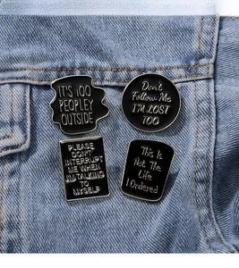 Macro shot of minimalist black enamel badges with gold trim on blue denim fabric