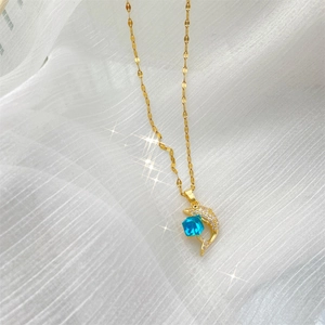Détail macro du collier pendentif dauphin doré avec pierre bleue sur tulle blanc