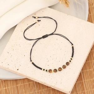 Handmade tiger eye stone bracelet with black beads and gold accents on a bamboo mat