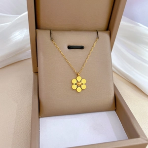 Detail of a golden six-petal flower necklace pendant resting inside a brown jewelry box