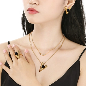 Detail of gold layered necklace and earrings set featuring black bead accents on model