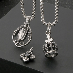 Close-up of vintage crown pendant and cross flower necklace in polished silver steel