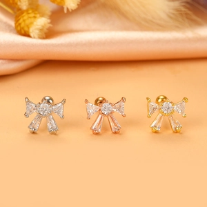 Macro detail of cross wing bow stud earrings in silver, rose gold, and gold plating