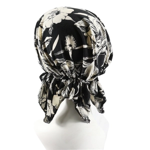 Women's pre-tied turban hat with white floral print on black fabric shown from back view