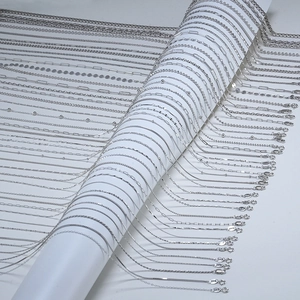 Various silver metal necklace styles displayed on a white spool for DIY jewelry
