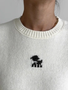 Dettaglio ravvicinato di maglione in maglia crema con trama morbida e motivo jacquard nero