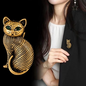 Vintage gold cat brooch with green gem eyes and striped texture on elegant suit jacket