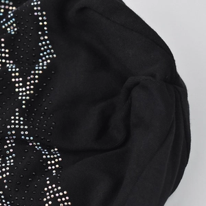 Macro shot of black knit beanie featuring sparkling rhinestone wave patterns and fine texture