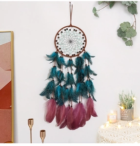 Detail of dream catcher with turquoise spotted feathers and magenta plumes on white wall