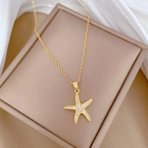 Luxurious gold star fish necklace with full crystals on beige jewelry box