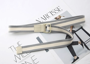 Detail of grey striped canvas belt with matte square buckle on minimalist magazine