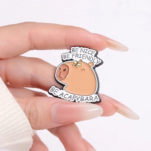 Cute Capybara enamel pin with motivational quotes held against a white knit sweater