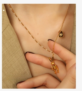 Detail of gold rabbit pendant and LUCKY charm on a stainless steel necklace