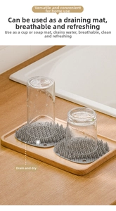 Gray silicone dish drying mat with round spiked design showing a glass cup draining