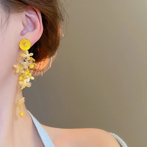 Detail view of long yellow flower tassel earrings with beads on model for fashion look