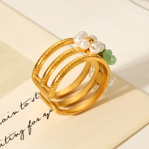 Detail of bohemian gold stainless steel ring with white pearls and green bead accents