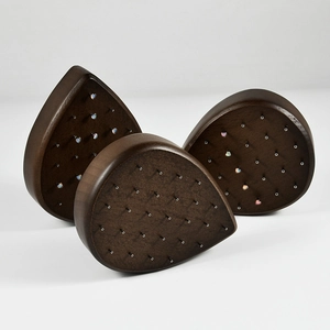 Macro view of teardrop walnut wood jewelry display stand with multiple stud holes