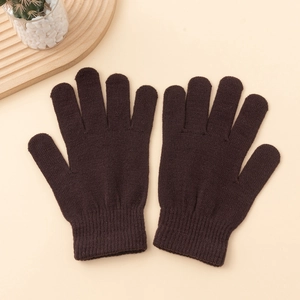 Detailed texture of dark brown knitted winter gloves with elastic ribbed cuffs on a beige surface