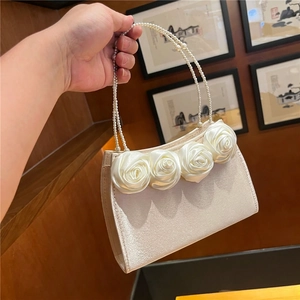 Detailed shot of satin rose accents and double pearl handles on the elegant handbag