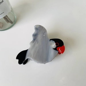 Detail of bird-shaped acetate hair claw clip featuring black, red, and marble textures