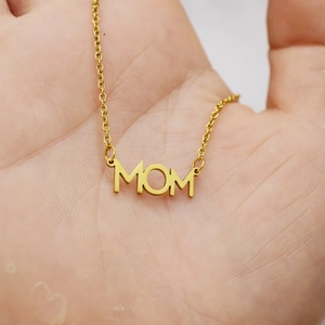 Gold stainless steel Mom pendant necklace held in hand to show scale and metal shine