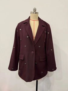 Close-up of deep purple blazer with silver heart embellishments and single-button detail