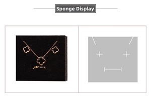 Detail view of rose gold clover necklace and earrings set in black sponge display insert