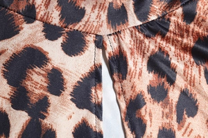 Macro view of leopard print dress detailing double-needle stitching and fabric texture