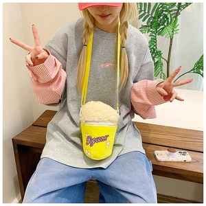 Mannequin portant un sac bandoulière en peluche en forme de pop-corn sur un banc.
