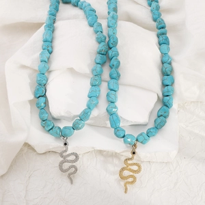 Detail of bohemian turquoise beaded necklaces featuring gold and silver snake pendants