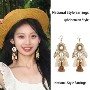 Detail of bohemian feather tassel earrings with wooden beads and golden leaf charm